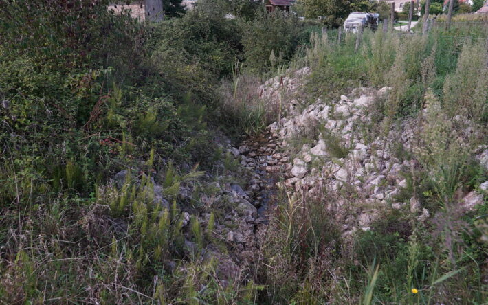 Canal empierré à la sortie du bassin de rétention conduit les eaux dans le ruisseau - Crédit photo : Banque des Territoires
