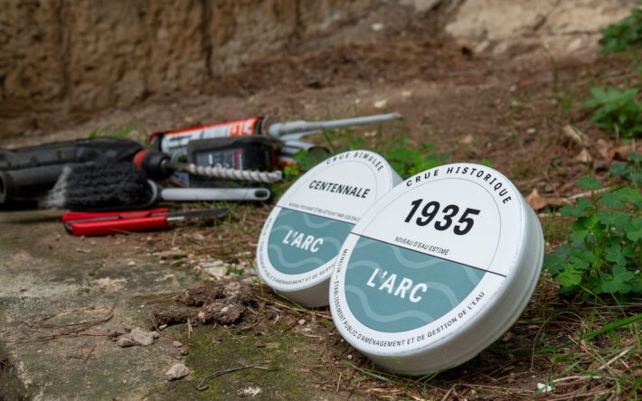 Repères de crues du bassin de l’Arc avant leur installation : les macarons indiquent la crue historique de 1935 et la crue centennale simulée. Un symbole de mémoire et de prévention du risque inondation. - Crédit photo : Kevin-Ouassel/Menelik