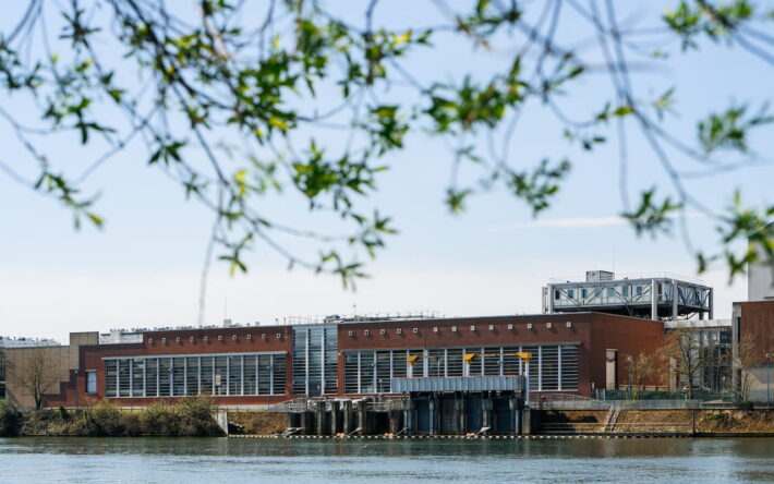 L’usine de Choisy-le-Roi, vue depuis la Seine. Implantée en bord de fleuve, l’usine s’inscrit au cœur du dispositif de production d’eau potable du SEDIF. -Crédits photo : SEDIF